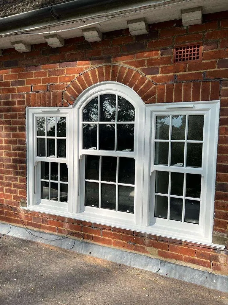 White sash windows with arched top light in a brick wall