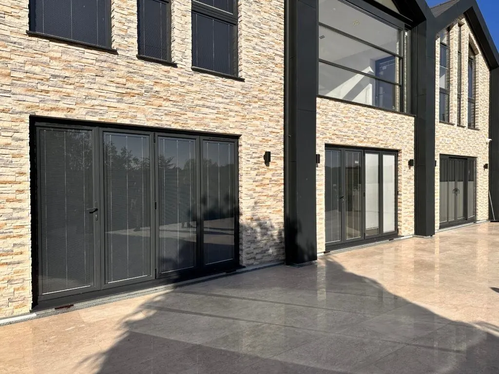 Grey aluminium sliding doors on a stone-clad rear extension